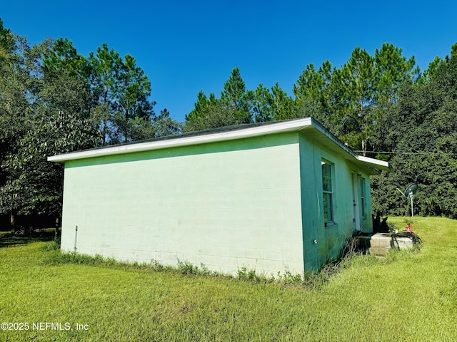 view of property exterior featuring concrete block siding and a lawn