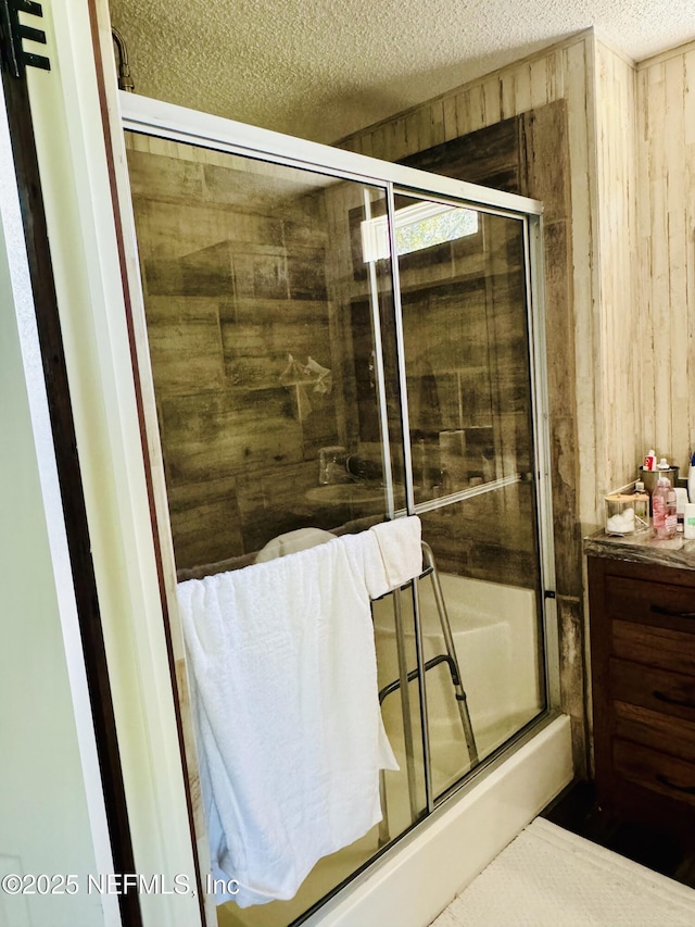 bathroom featuring a textured ceiling, tiled shower, and wooden walls