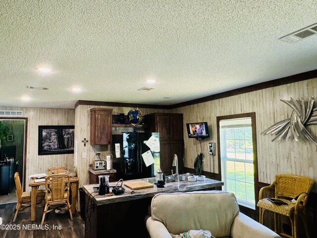 living area featuring dark wood-style flooring, visible vents, and a textured ceiling