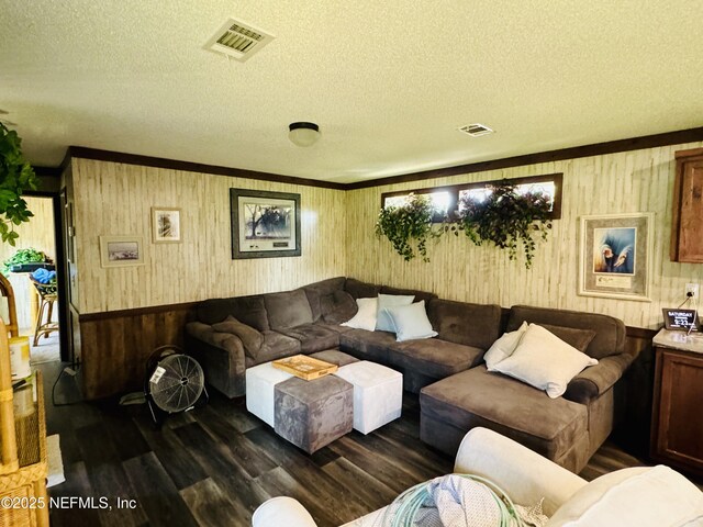 living room with a textured ceiling, visible vents, dark wood-style flooring, and ornamental molding