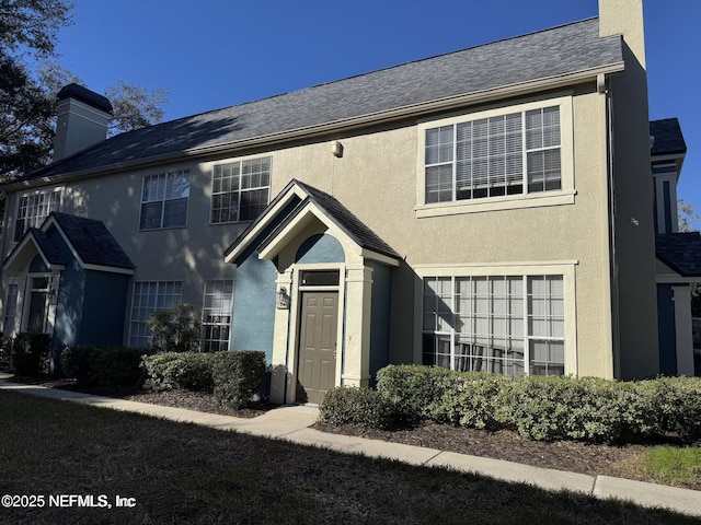 view of front of house with a chimney and stucco siding