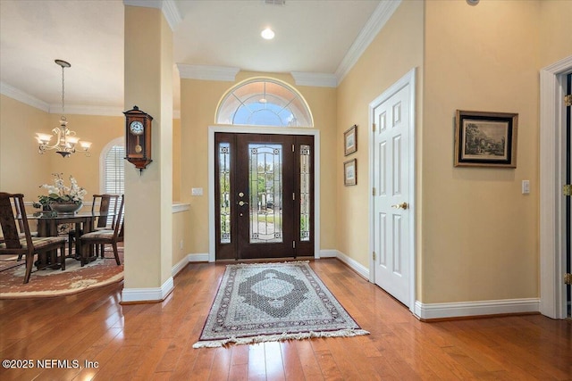 foyer entrance with crown molding, light wood-style flooring, and a healthy amount of sunlight