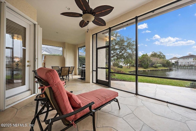 sunroom with a water view and a ceiling fan