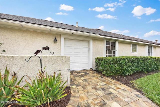 property entrance featuring a shingled roof and stucco siding