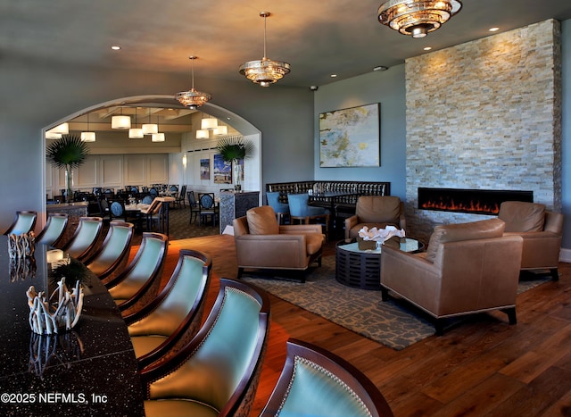 living room featuring arched walkways, a fireplace, recessed lighting, and wood finished floors