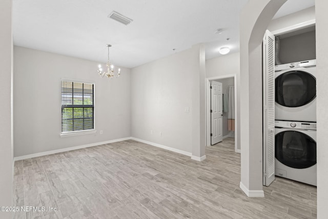 laundry room featuring a notable chandelier, stacked washer / drying machine, visible vents, light wood-type flooring, and laundry area