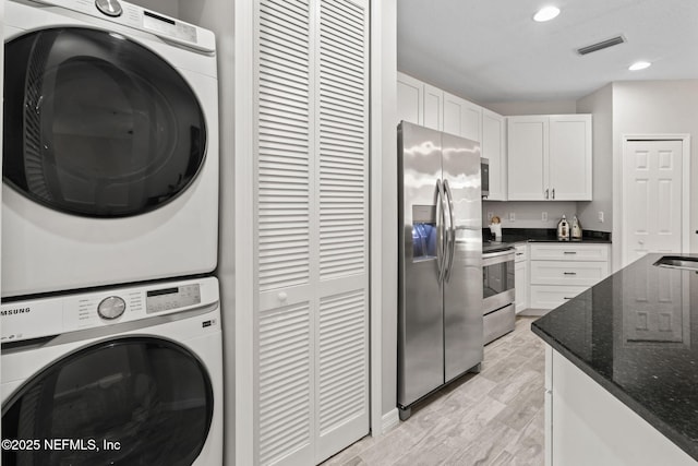 laundry room featuring laundry area, visible vents, stacked washer and clothes dryer, light wood-style floors, and recessed lighting