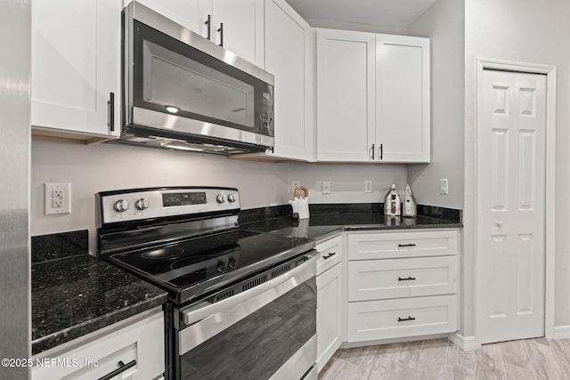 kitchen featuring white cabinetry, appliances with stainless steel finishes, and dark stone counters