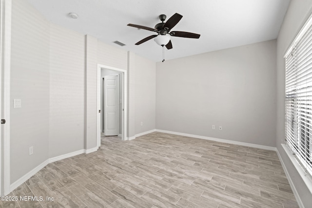 empty room with a ceiling fan, baseboards, visible vents, and light wood finished floors