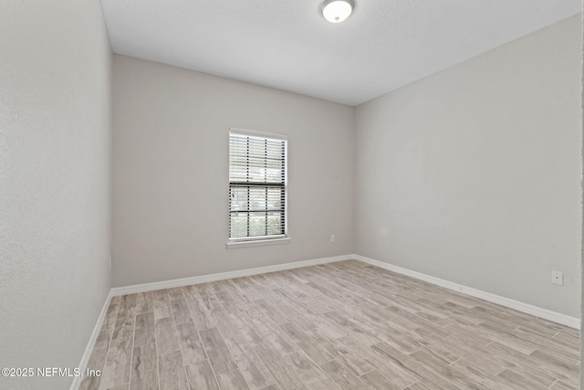 spare room with baseboards and light wood finished floors