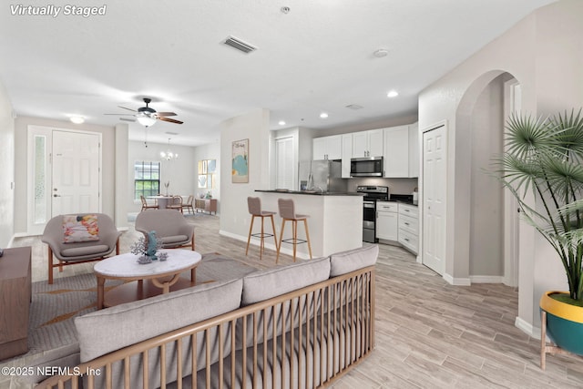 living area with arched walkways, recessed lighting, visible vents, light wood-style flooring, and baseboards