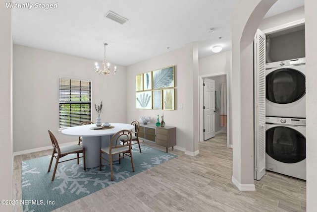 dining room featuring visible vents, an inviting chandelier, stacked washer / dryer, wood finished floors, and baseboards