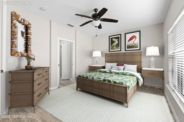 bedroom featuring ceiling fan, light wood-style flooring, visible vents, and baseboards