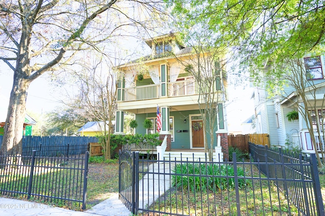 view of front of house featuring a porch, a gate, a balcony, and a fenced front yard