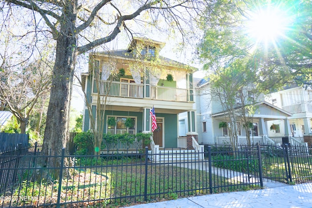 american foursquare style home featuring covered porch, a fenced front yard, and a balcony