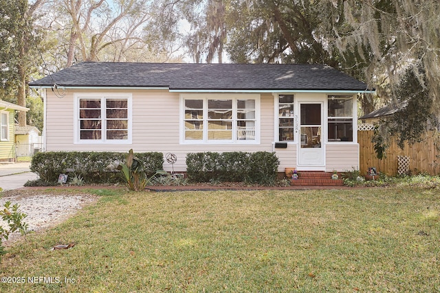 view of front of house with entry steps, fence, and a front yard