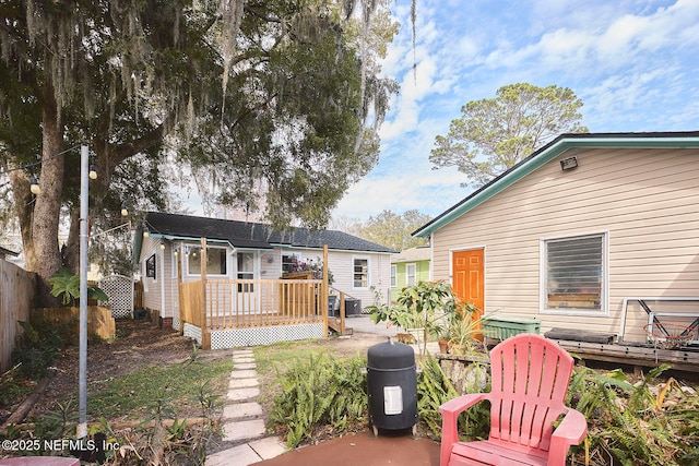 rear view of property featuring fence and a deck