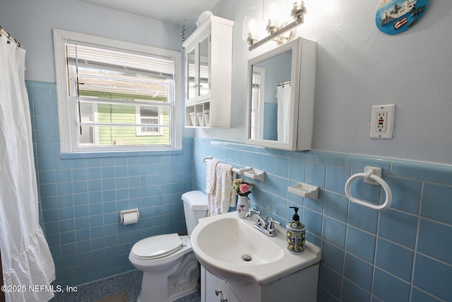 full bath featuring wainscoting, vanity, toilet, and tile walls