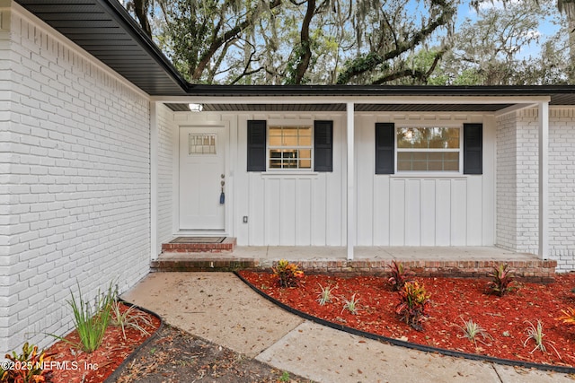 view of exterior entry with brick siding and board and batten siding