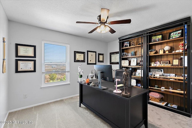 office space featuring a ceiling fan, light colored carpet, a textured ceiling, and baseboards