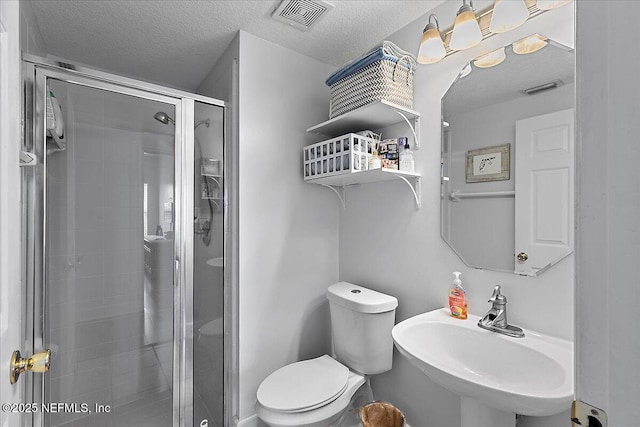 bathroom featuring a stall shower, visible vents, toilet, a textured ceiling, and a sink