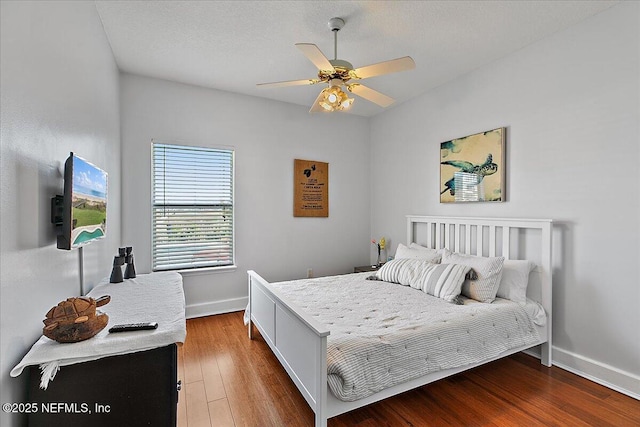 bedroom featuring ceiling fan, a textured ceiling, baseboards, and wood finished floors