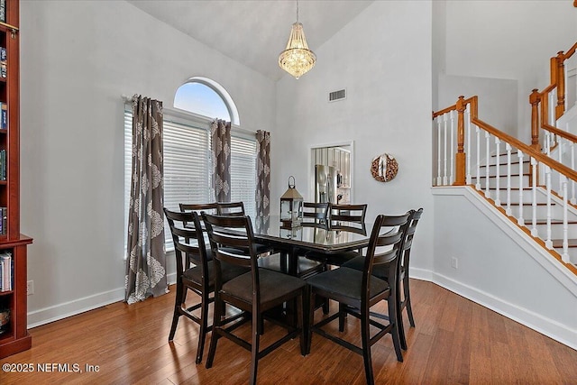 dining space with stairs, visible vents, baseboards, and wood finished floors