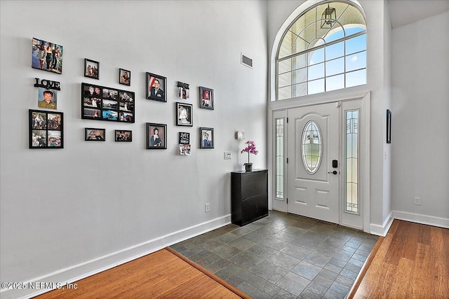 foyer entrance featuring baseboards, visible vents, and dark wood-type flooring