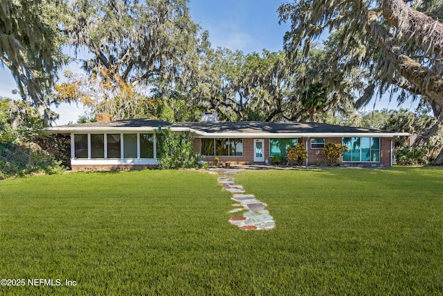 view of front of home with a front yard, brick siding, and a chimney