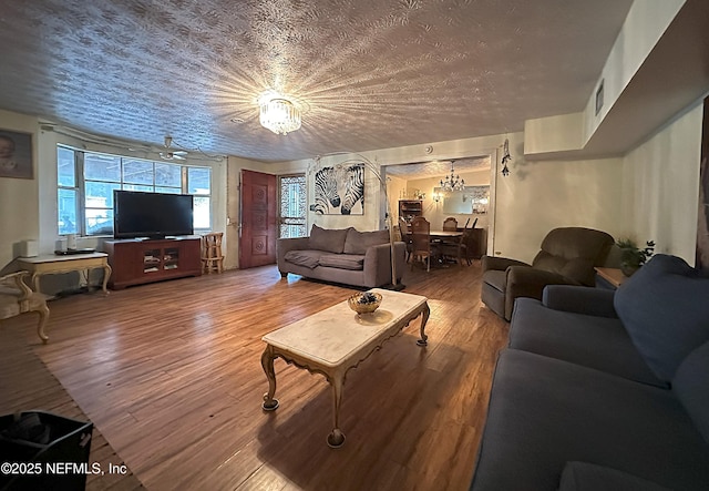 living area featuring a textured ceiling, wood finished floors, and a notable chandelier