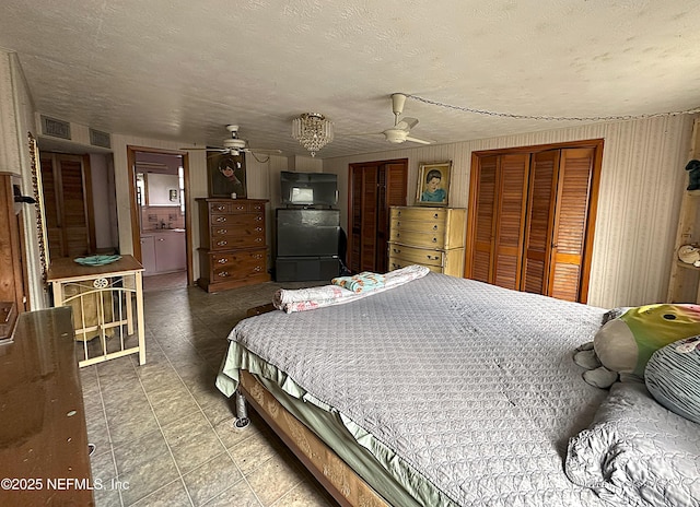 bedroom with ceiling fan, a textured ceiling, and fridge