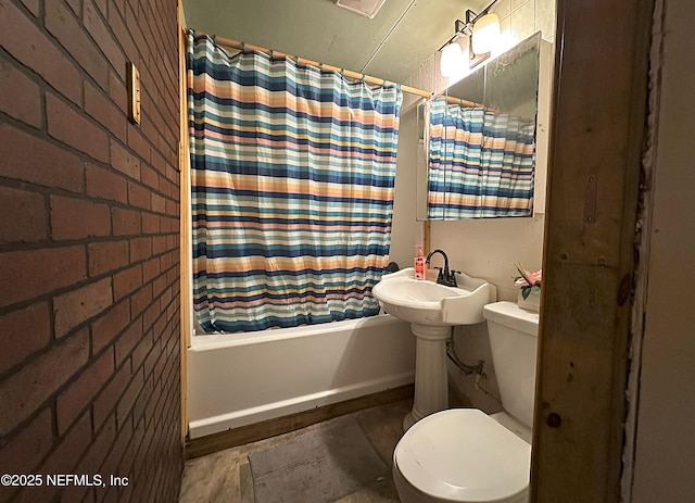 bathroom with toilet, brick wall, a sink, baseboards, and shower / bathtub combination with curtain