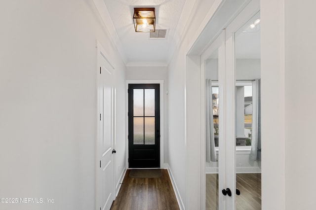 entryway with visible vents, crown molding, baseboards, and wood finished floors