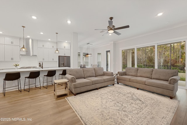 living room featuring ornamental molding, recessed lighting, light wood finished floors, and a ceiling fan