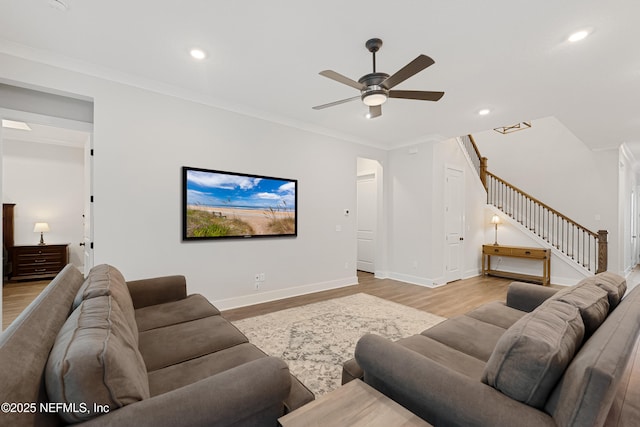 living area featuring light wood-style floors, crown molding, baseboards, and stairs