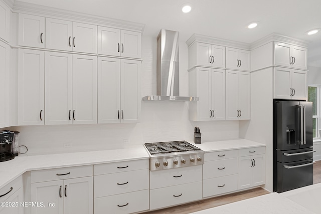 kitchen featuring white cabinets, wall chimney range hood, and stainless steel appliances