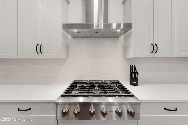 kitchen with stainless steel gas cooktop, wall chimney exhaust hood, white cabinetry, and decorative backsplash