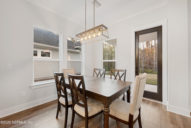 dining room featuring baseboards, visible vents, and light wood-style floors