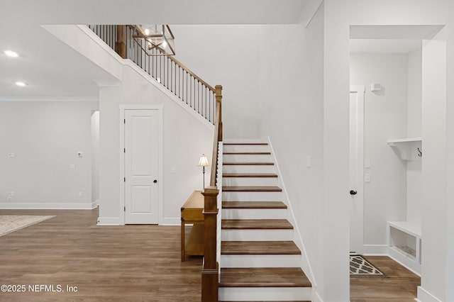 stairs featuring crown molding, baseboards, wood finished floors, and recessed lighting