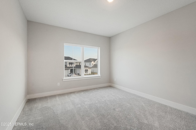 carpeted empty room with baseboards