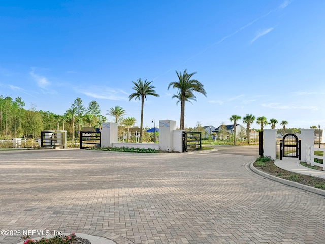 view of road featuring a gate, a gated entry, and curbs