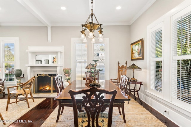 dining room featuring a warm lit fireplace, ornamental molding, wood finished floors, beamed ceiling, and a notable chandelier