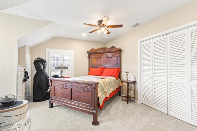 bedroom with visible vents, light colored carpet, ceiling fan, vaulted ceiling, and a closet