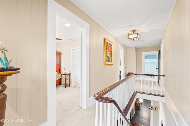 corridor featuring light colored carpet and an upstairs landing