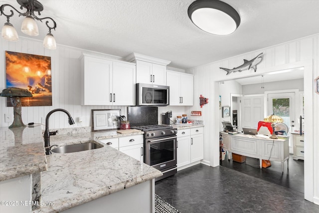 kitchen featuring stainless steel appliances, light stone counters, a sink, and white cabinets