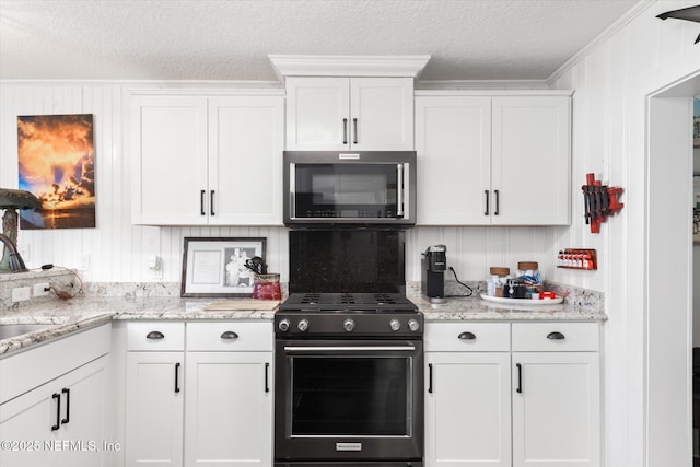 kitchen featuring stainless steel microwave, white cabinetry, and range with gas stovetop