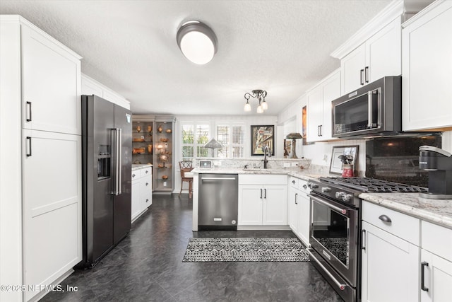 kitchen featuring a peninsula, light stone countertops, high quality appliances, and white cabinets