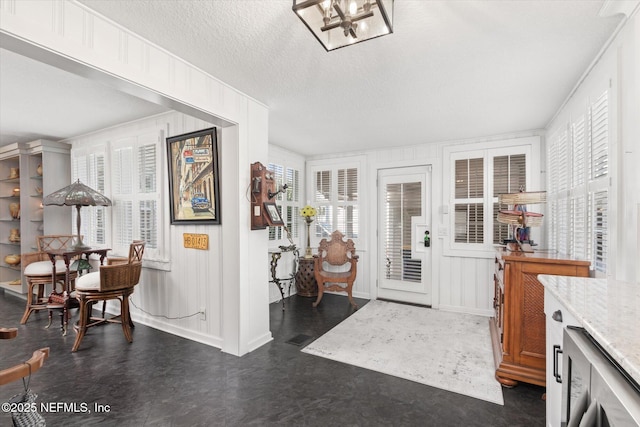 entryway featuring a textured ceiling, beverage cooler, baseboards, and an inviting chandelier