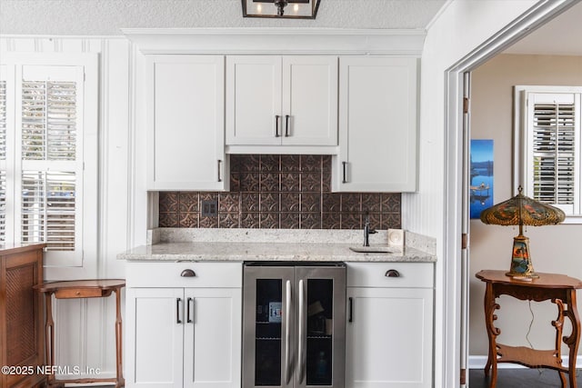 bar featuring a textured ceiling, wine cooler, and decorative backsplash