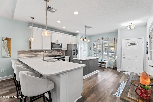 kitchen featuring hanging light fixtures, appliances with stainless steel finishes, a peninsula, and light countertops